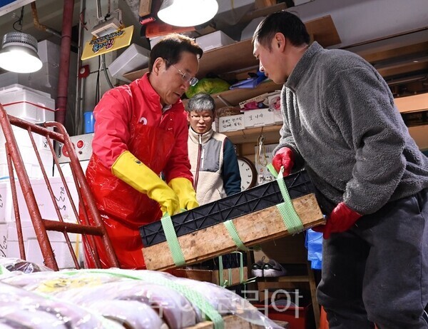 국민의힘 유정복 인천시장 선거 예비후보가 30일 오전 인천시 중구 인천종합어시장 앞에서 트럭에 실려있던 생선 상자를 어시장 상인에게 넘겨주는 일을 돕고 있다.