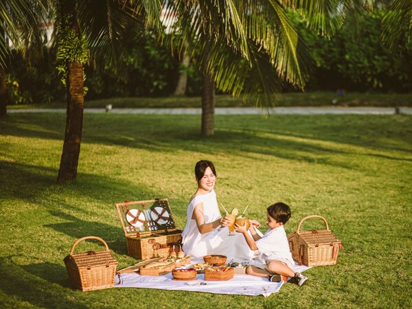 Mom and kid are enjoying picnic in the garden