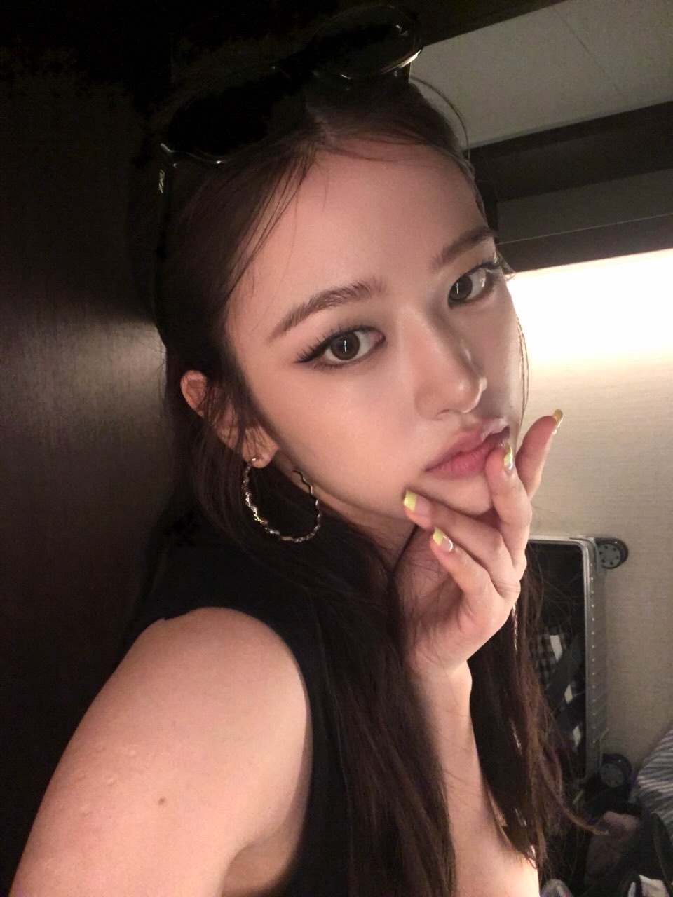 안유진이 블랙 탱크탑 차림으로 거울 앞 클로즈업 셀카를 찍었다. 옐로 네일과 후프 이어링이 시선을 끈다. / 사진=안유진 인스타그램 @_yujin_an