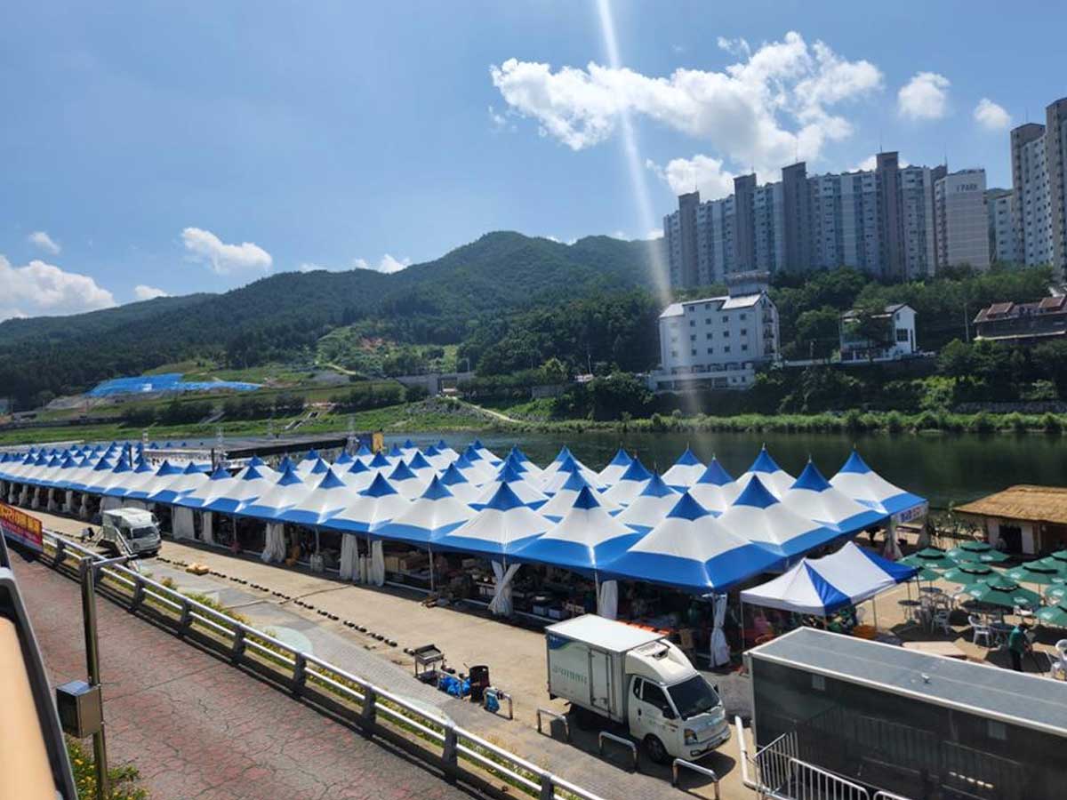 행사 부스들이 길게 줄지어 늘어선 홍천찰옥수수축제장의 활기찬 전경 사진. / 홍천축제