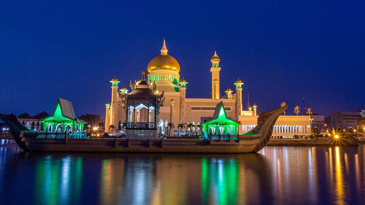 화려한 조명이 켜진 고요한 밤의 강변 위로 배와 웅장한 이슬람 사원. / Fajar Hengki Wijaya-shutterstock