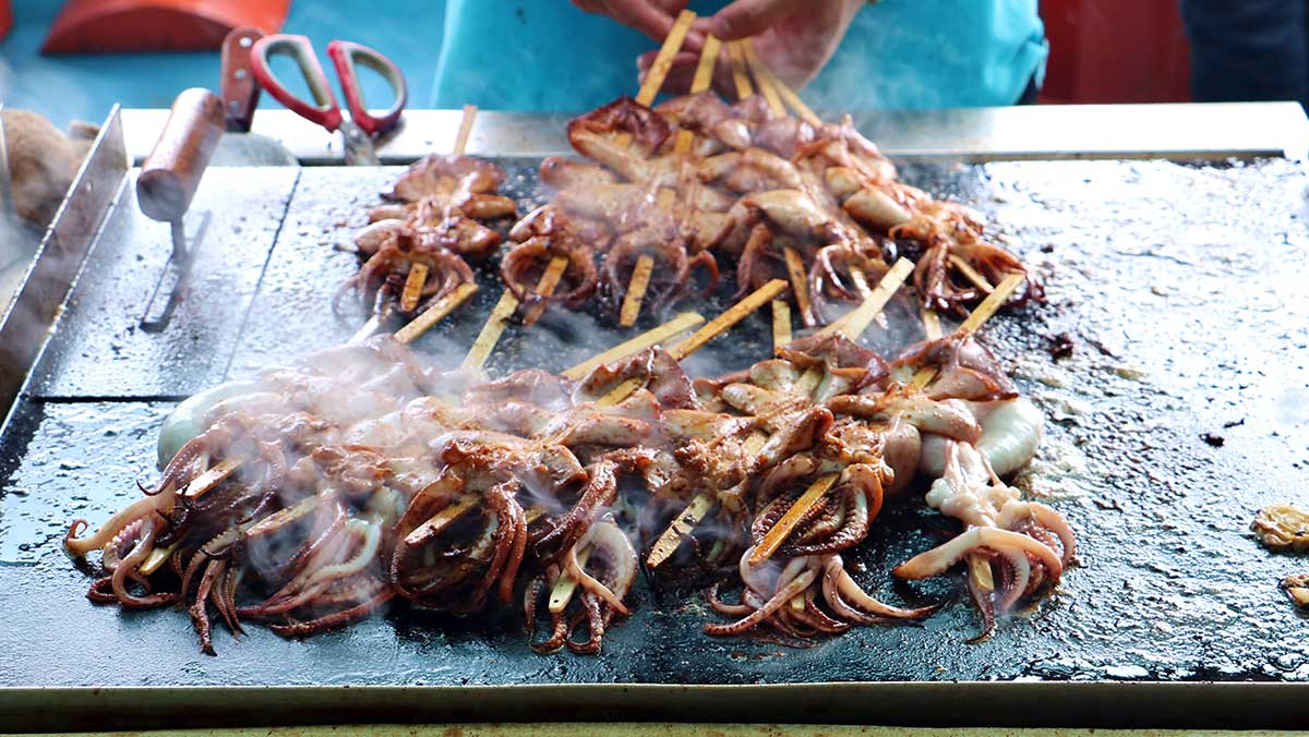 대형 철판 위에서 김을 내며 맛있게 구워지는 오징어 꼬치구이다. / Yu Xichao-shutterstock