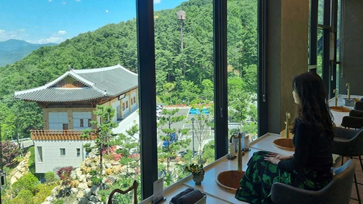 한옥 전경을 바라보며 따뜻한 약탕에 발을 담글 수 있는 실내 족욕 체험 공간. / 산청 동의보감촌