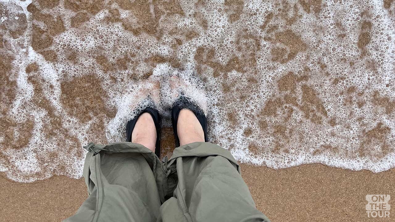 낙산해수욕장 백사장에서 찰랑이는 파도에 발을 담근 모습. / 온더투어