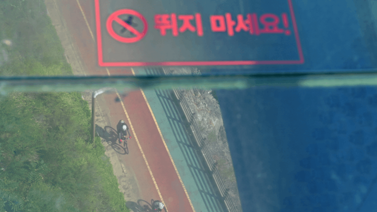 투명한 유리 바닥 너머로 발밑의 아라뱃길 자전거 도로가 내려다보이는 모습. / 인천투어