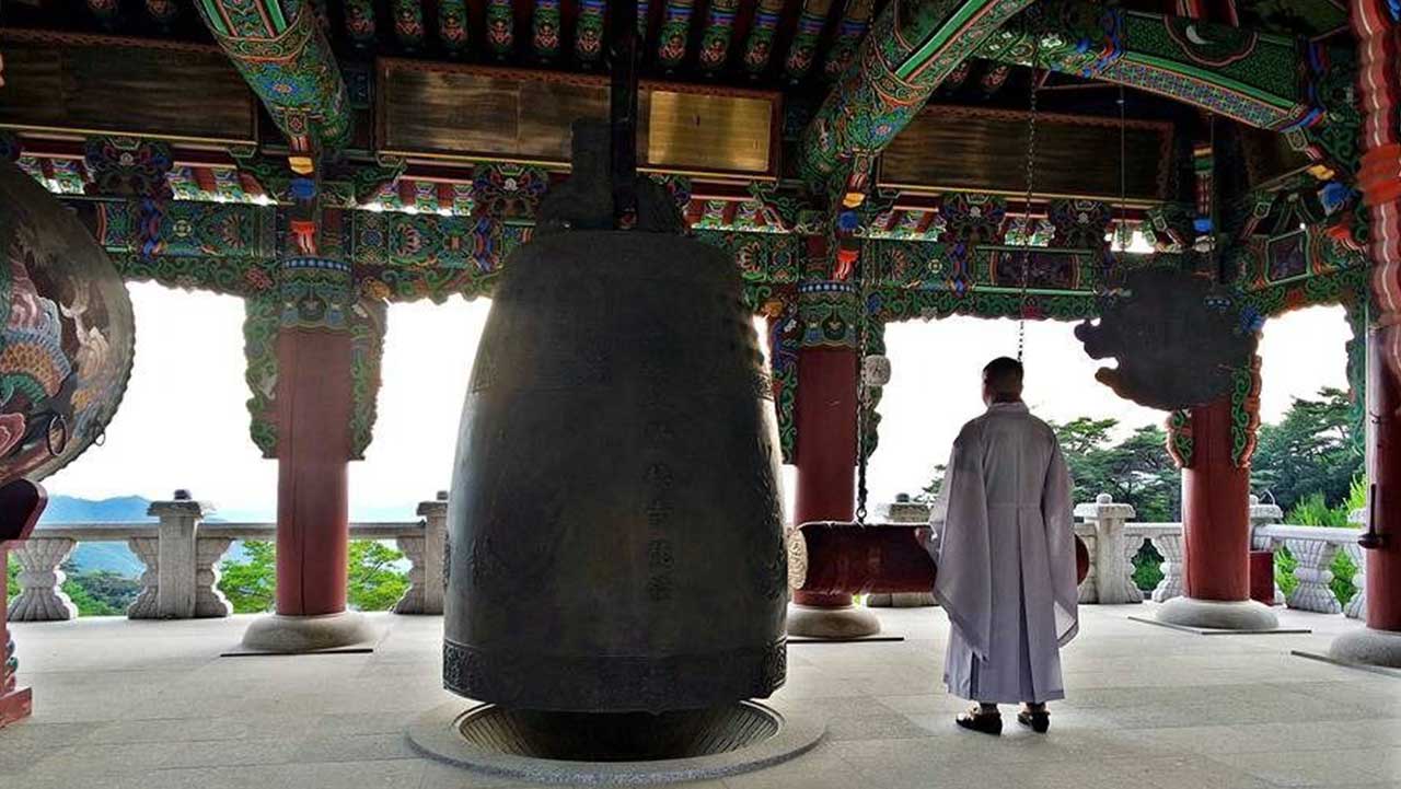 거대한 범종과 함께 산자락 풍경을 바라보는 스님의 모습. / 한국관광콘텐츠랩