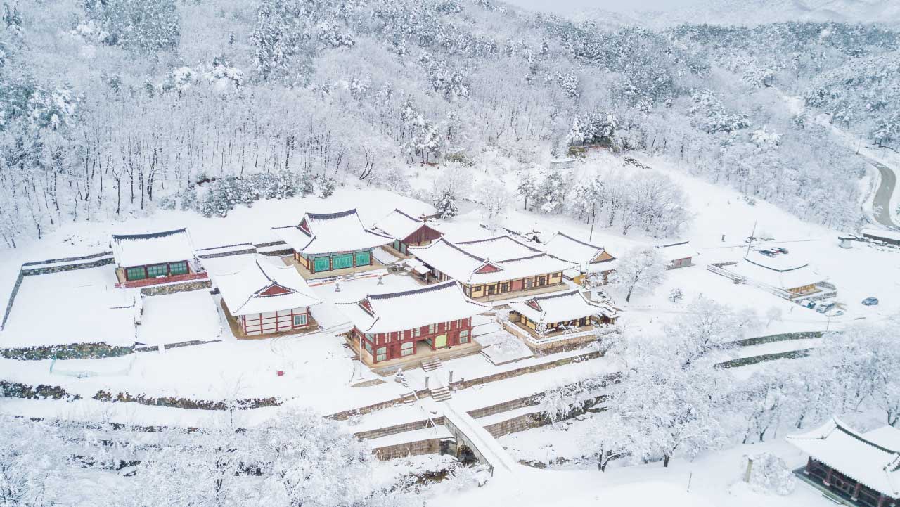 눈이 전각과 넓은 옛 절터를 아늑하게 감싸 안은 건봉사 겨울 항공 뷰. / 고성군 문화관광