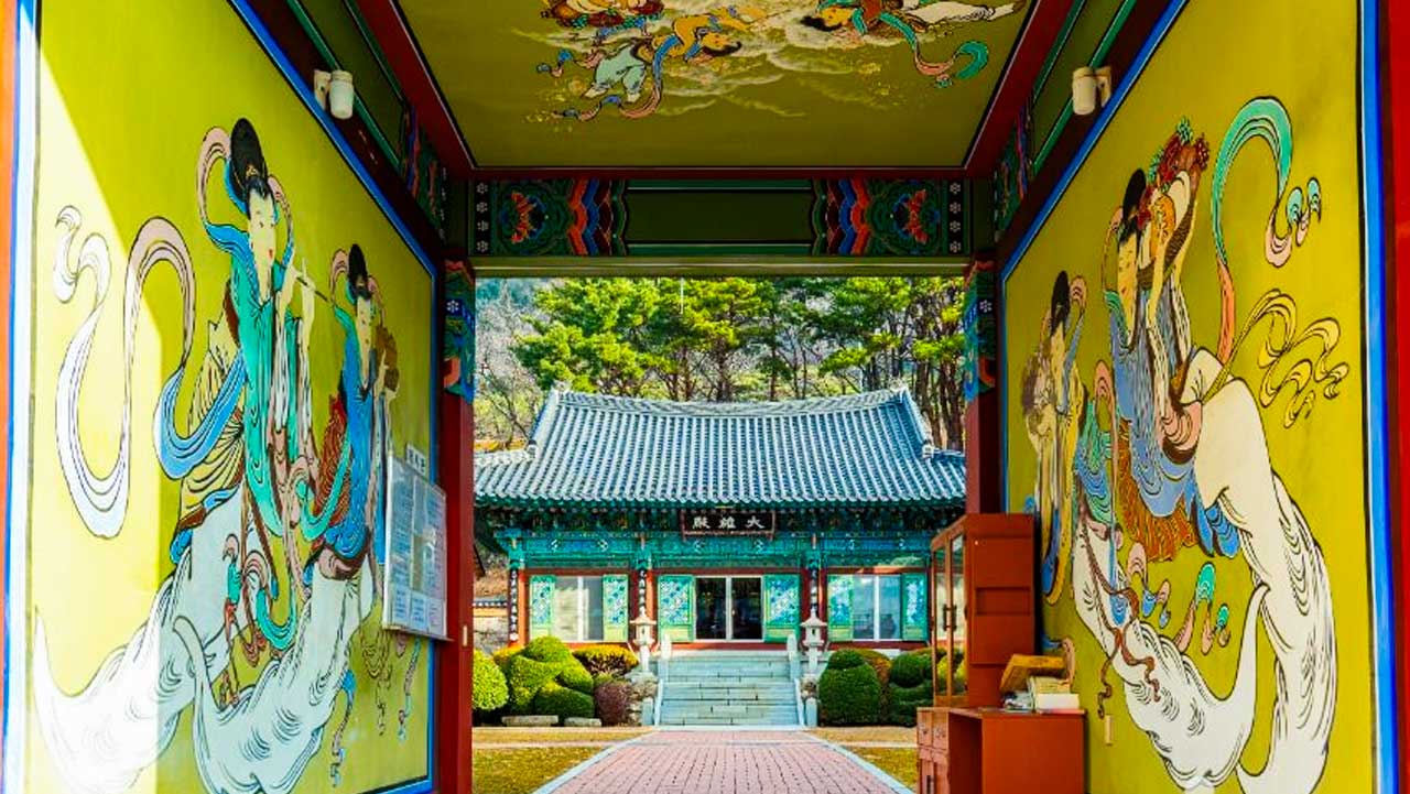 화려한 비천상 벽화가 그려진 통로 프레임 너머로 보이는 고즈넉한 법당 모습. / 한국관광공사