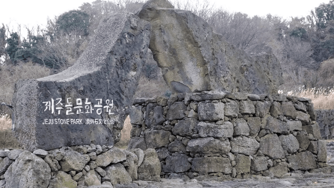 투박한 현무암 돌담 위에 각인된 제주돌문화공원의 입구 표지석 전경. / 비짓제주