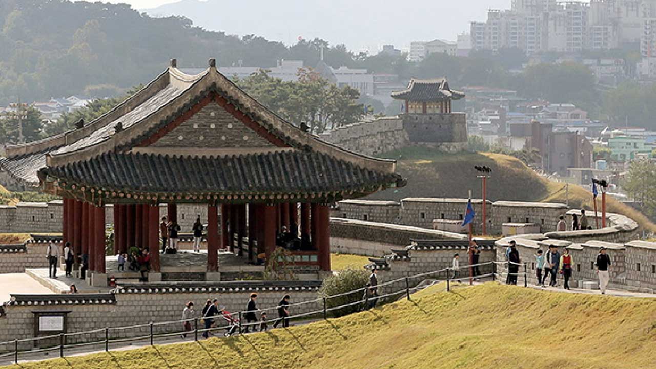 능선을 따라 정갈하게 이어지는 성벽 길과 성곽 위에 고풍스럽게 들어선 누각 풍경. / 수원화성관광