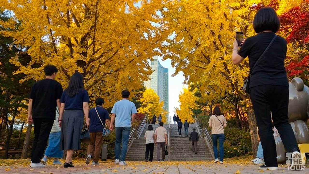 은행나무길을 걸으며 사진을 찍고 가을 산책을 즐기는 방문객들 모습. (AI 생성) / 온더투어
