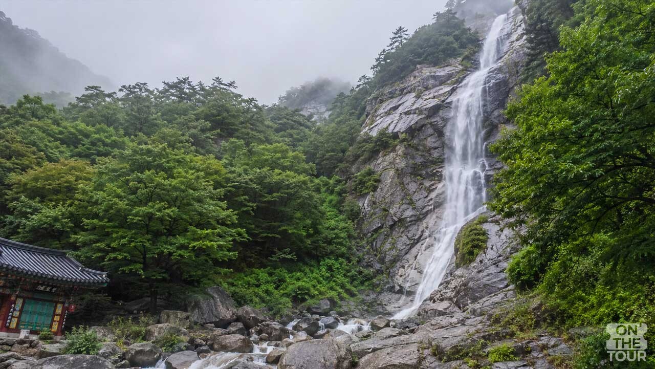 울창한 숲과 바위 절벽 사이로 시원한 물줄기가 내리쏟아지는 양산 홍룡폭포와 홍룡사. (AI 생성) / 온더투어