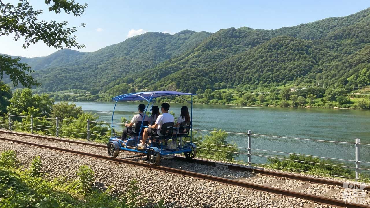 북한강을 바라보며 옛 경춘선 철길을 달리는 강촌레일파크 레일바이크. (AI 생성) / 온더투어