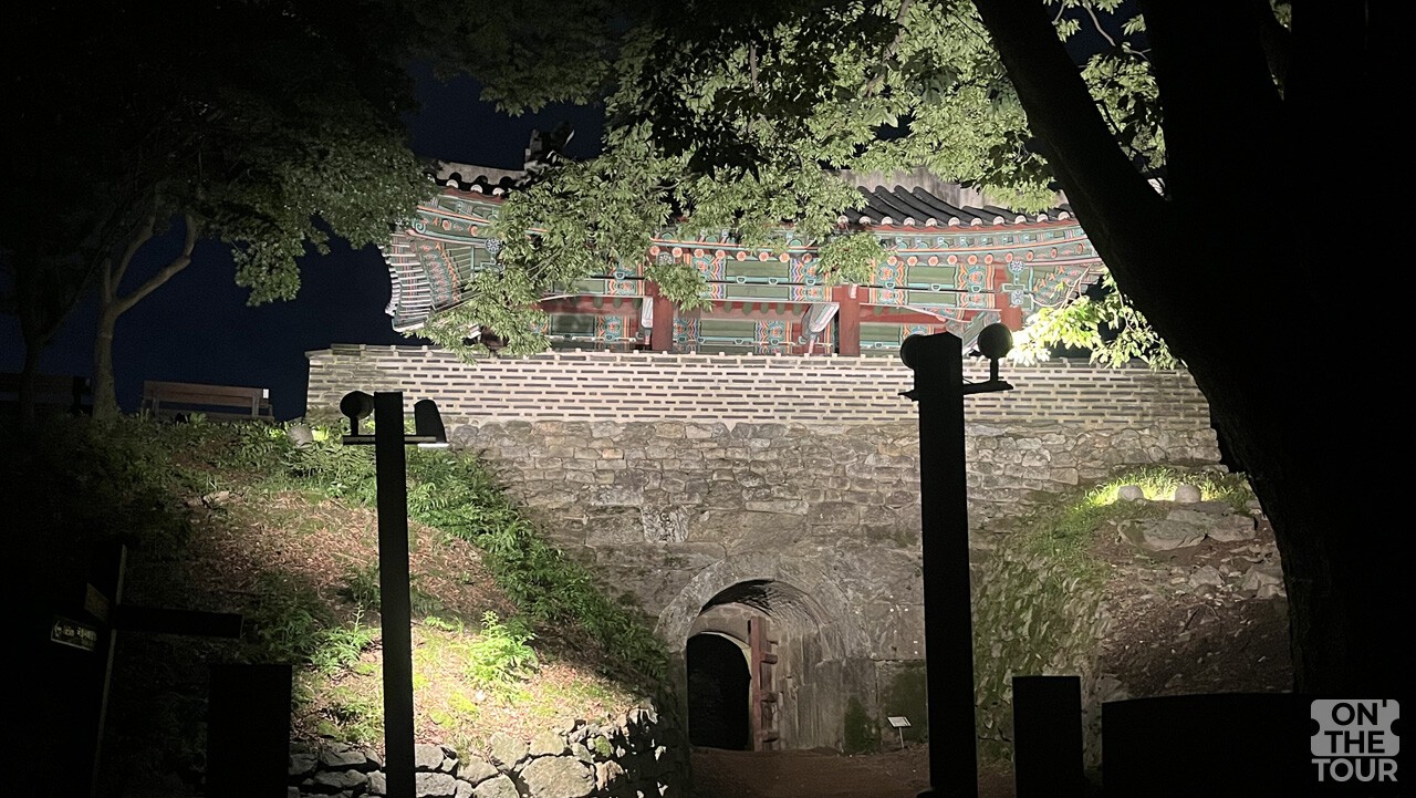 야간 조명이 켜진 남한산성 서문 우익문. 성문 아래 통로와 오래된 성벽이 함께 보인다. / 온더투어
