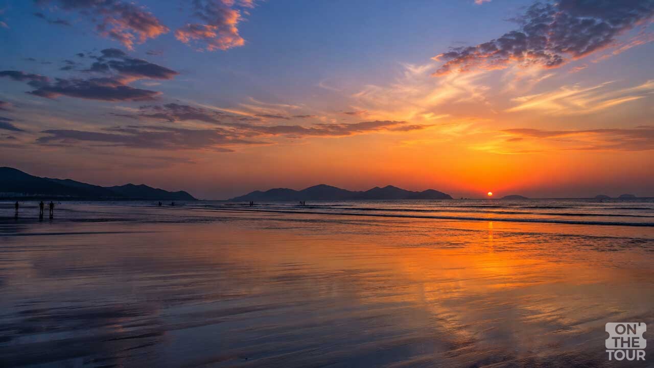 해가 수평선 가까이 내려앉은 다대포해수욕장의 넓은 갯벌과 노을 풍경. (AI 생성) / 온더투어