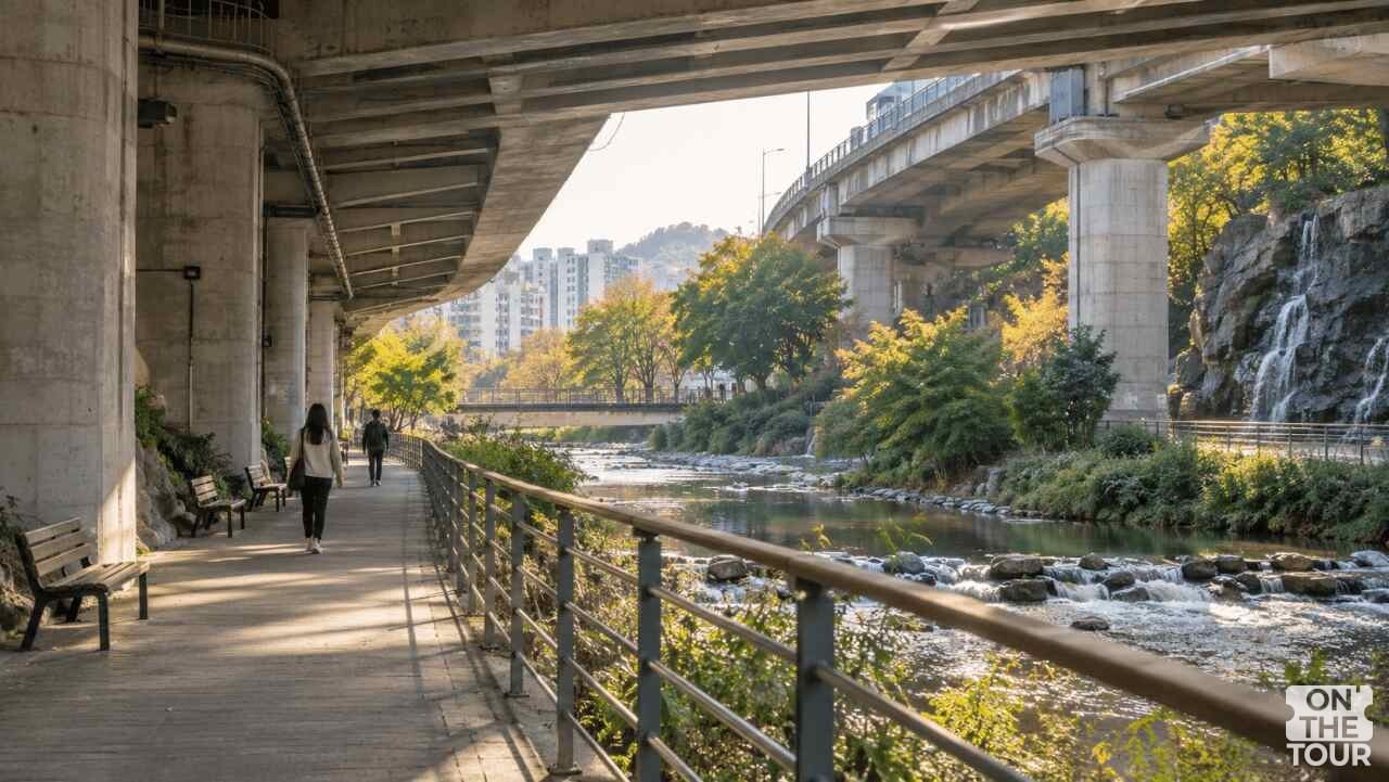 내부순환로 교각 아래 홍제천 물길을 따라 산책로와 벤치가 이어지는 모습. (AI 생성) / 온더투어