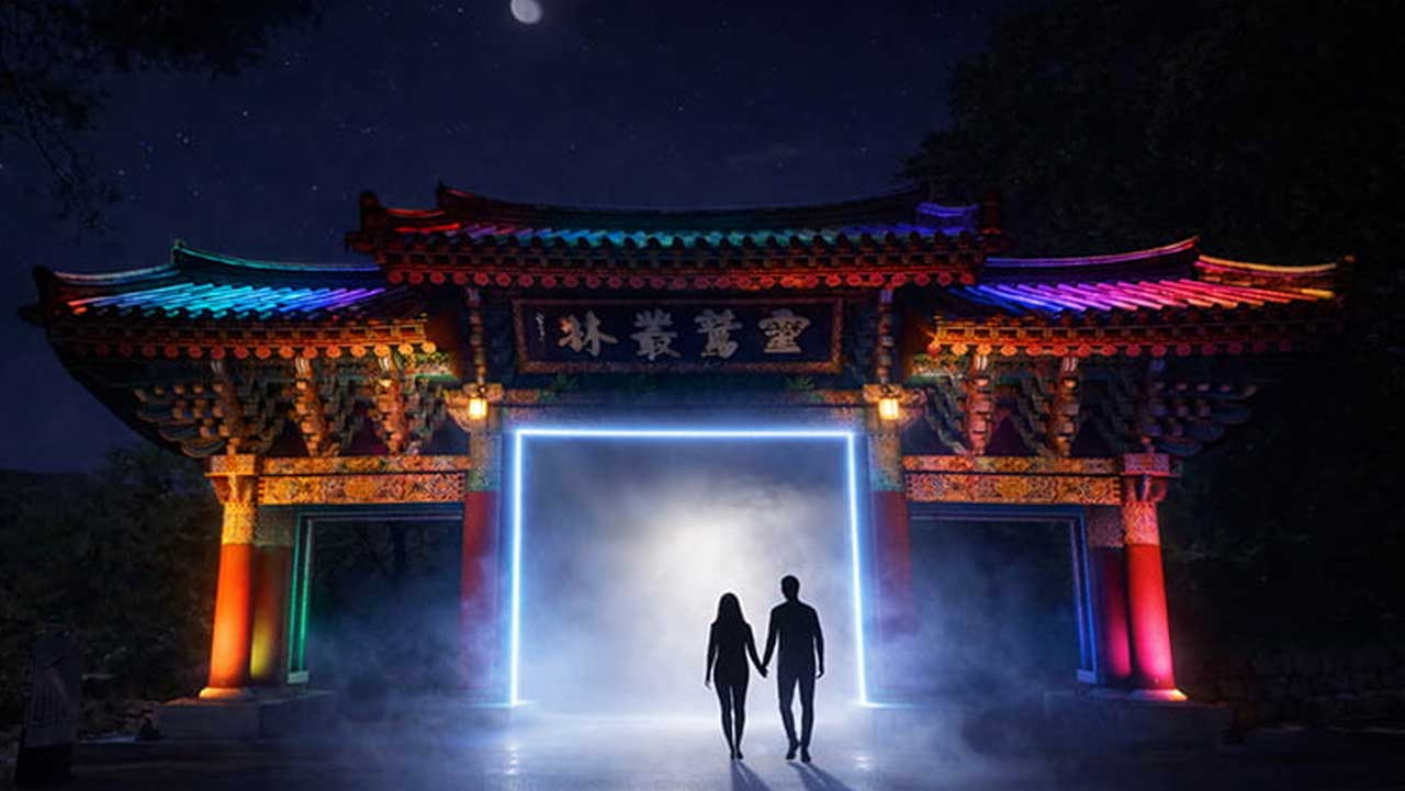 빛으로 만든 문을 향해 걸어가는 관람객들 뒤로 통도사 산문이 환하게 밝혀져 있다. / 2026 국가유산 미디어아트 양산 통도사