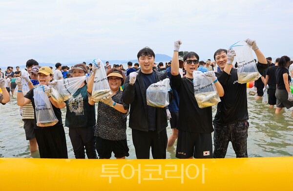 관광객들이 전어축제장에 직접 작은 전어를 들어 보이며 환한 미소를 짓고 있다./사진=보성군