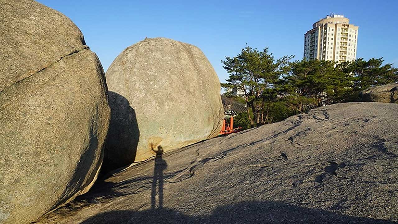 거대한 둥근 바위들 너머로 속초 시내의 고층 건물이 어우러진 이색적인 풍경. / 속초시