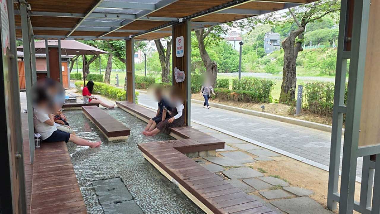 방문객들이 나무 데크에 앉아 족욕을 즐기는 수안보온천 족욕길. / 충주시 공식 SNS