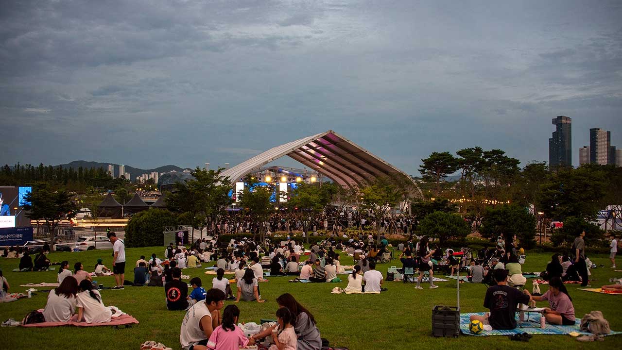 잔디밭에 돗자리를 펴고 모여앉아 대형 야외 무대의 공연을 즐기는 수많은 시민들의 모습. / 세종시 공식 SNS