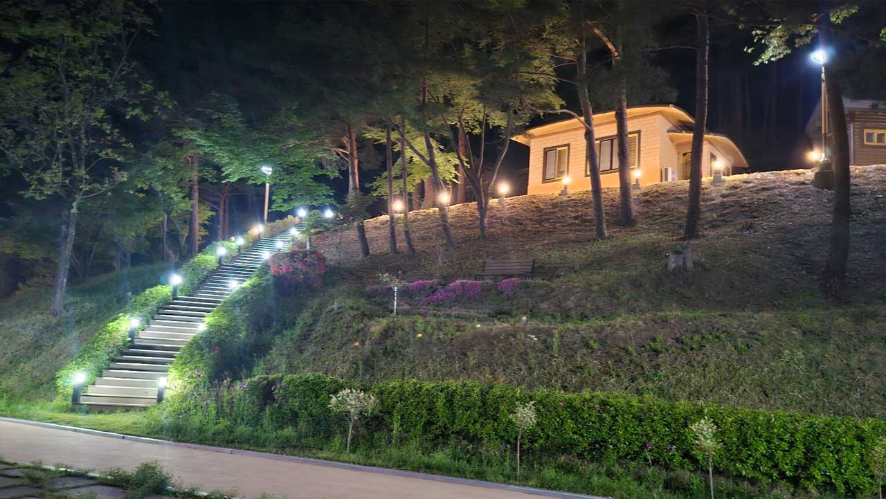 야간 조명이 켜진 구수곡자연휴양림의 숲속 숙소와 계단 산책로. / 숲나들e