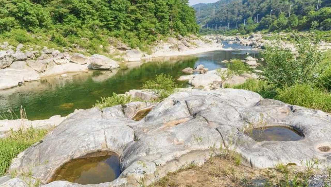 내린천 강변의 넓은 암반에 둥근 포트홀이 자리해 있고 뒤편으로 물길이 이어진다. / 대한민국 구석구석