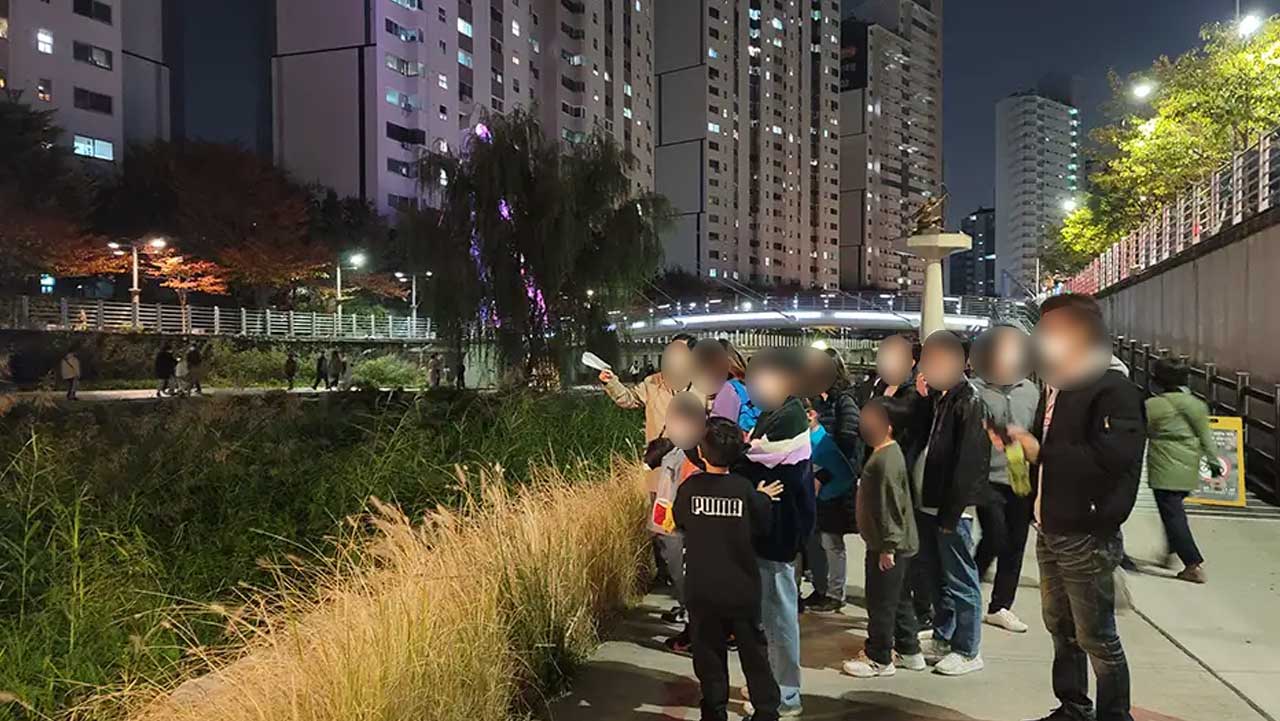 억새가 자란 하천 산책로에서 관람객들이 작품 설명을 듣고 있다. / 노원문화재단