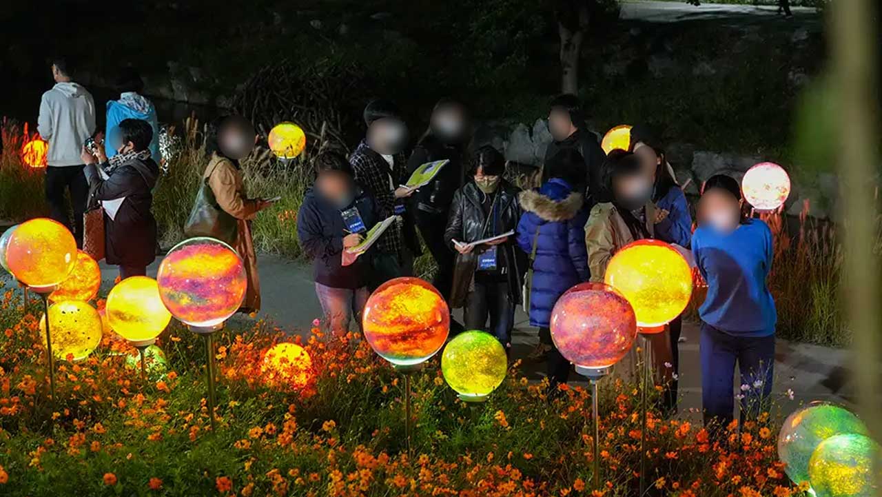 주황색 꽃밭 사이에 놓인 구형 조명 작품이 저마다 다른 빛깔로 켜져 있다. / 노원문화재단