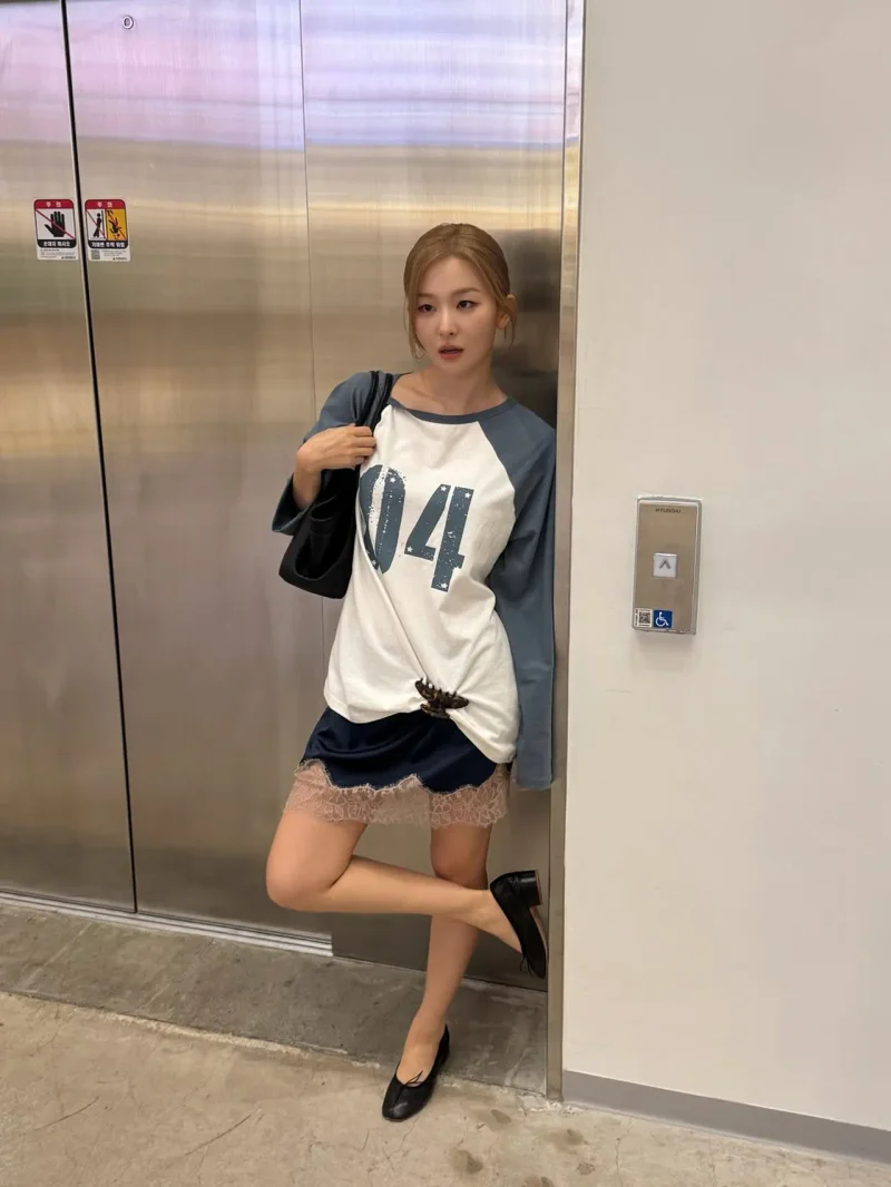 엘리베이터 앞에서 래글런 티셔츠와 레이스 슬립 스커트 룩을 선보인 모습 / 사진=슬기 인스타그램