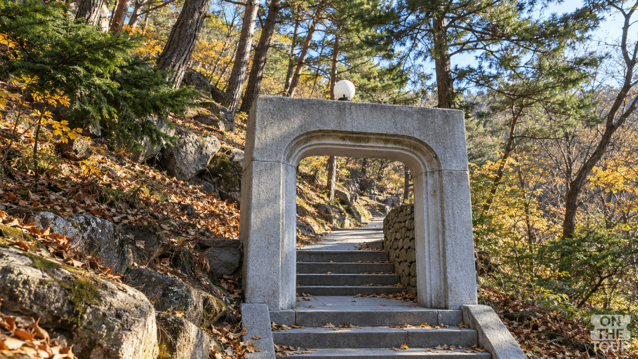 경남 양산 홍룡사 경내 석문 사이로 이어지는 돌계단과 낙엽이 내려앉은 숲 풍경. (AI 생성) / 온더투어