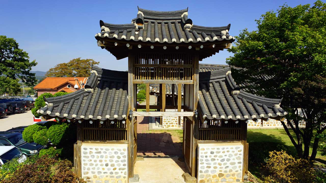 마당 입구에 기와지붕을 얹은 문루가 서 있고, 돌을 박아 쌓은 벽이 양옆으로 이어져 있다. / 강화군 문화관광