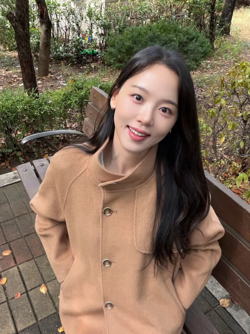 강한나가 벤치에 앉아 카멜 코트 차림으로 미소 짓고 있다. / 사진=강한나 인스타그램