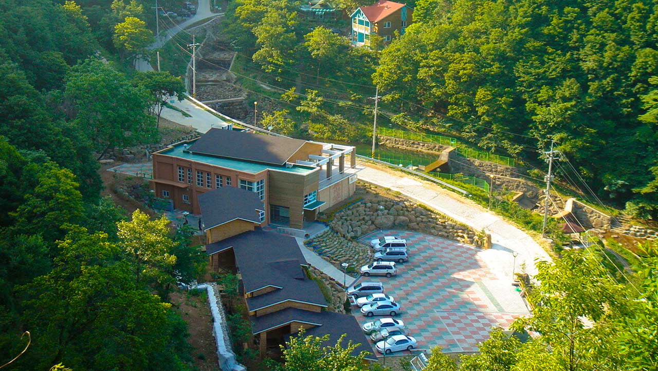 영동 민주지산자연휴양림 숙박시설과 주차 공간을 푸른 숲 사이로 내려다본 모습. / 자연휴양림