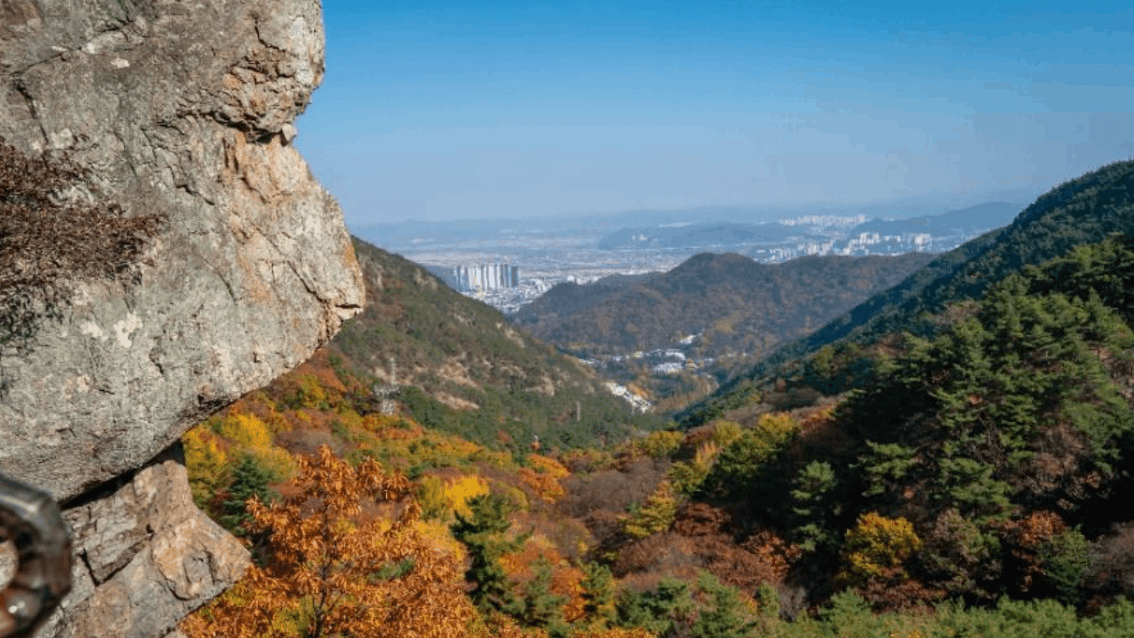 구미 금오산 도선굴 부근 암벽 너머로 단풍 든 산자락과 멀리 도심이 내려다보인다. / 대한민국 구석구석