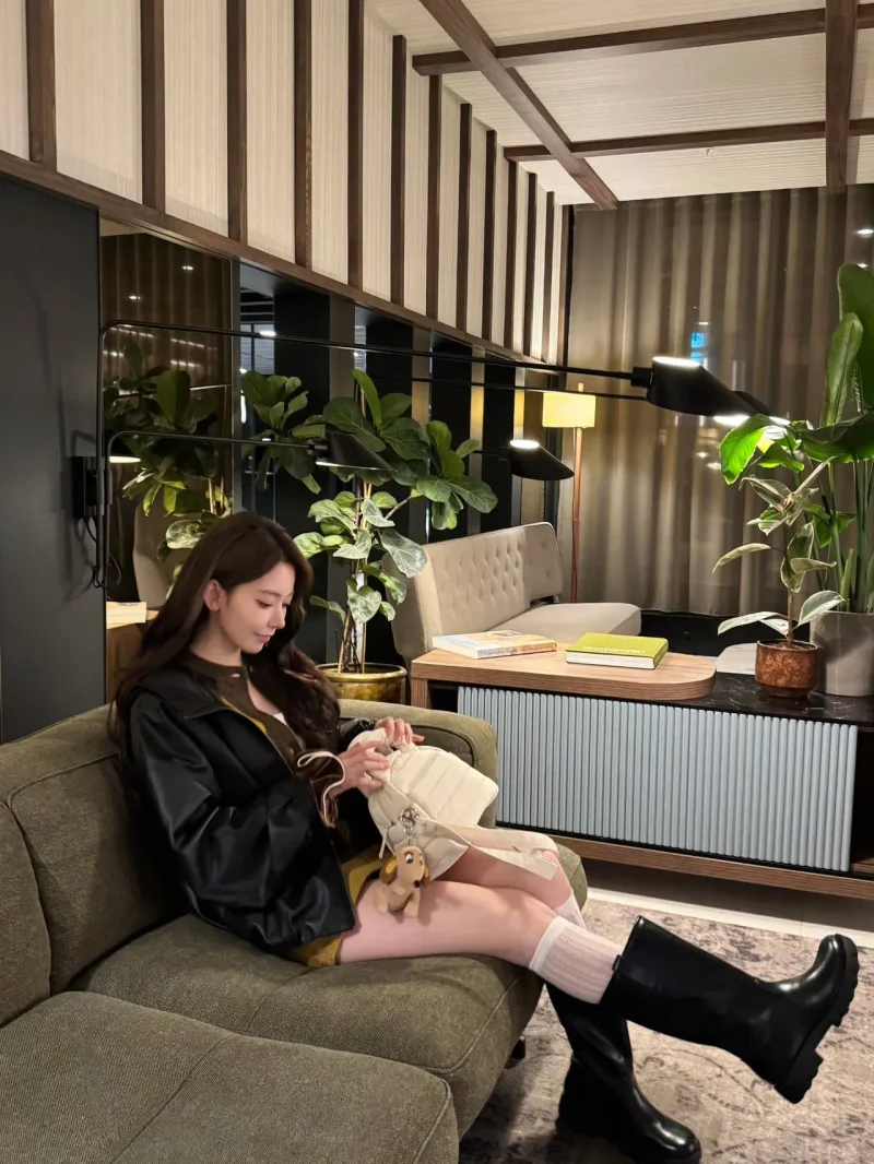 사쿠라가 소파에 앉아 크림색 가방을 열어 보며 롱부츠와 니삭스 차림을 드러냈다. / 사진=사쿠라 인스타그램 @39saku_chan