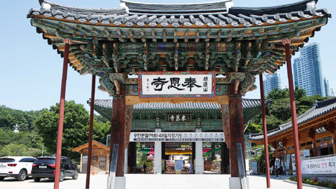 봉은사 입구 일주문. '奉恩寺' 현판이 걸려 있고 뒤로 삼성동 빌딩이 보인다. / 비짓서울