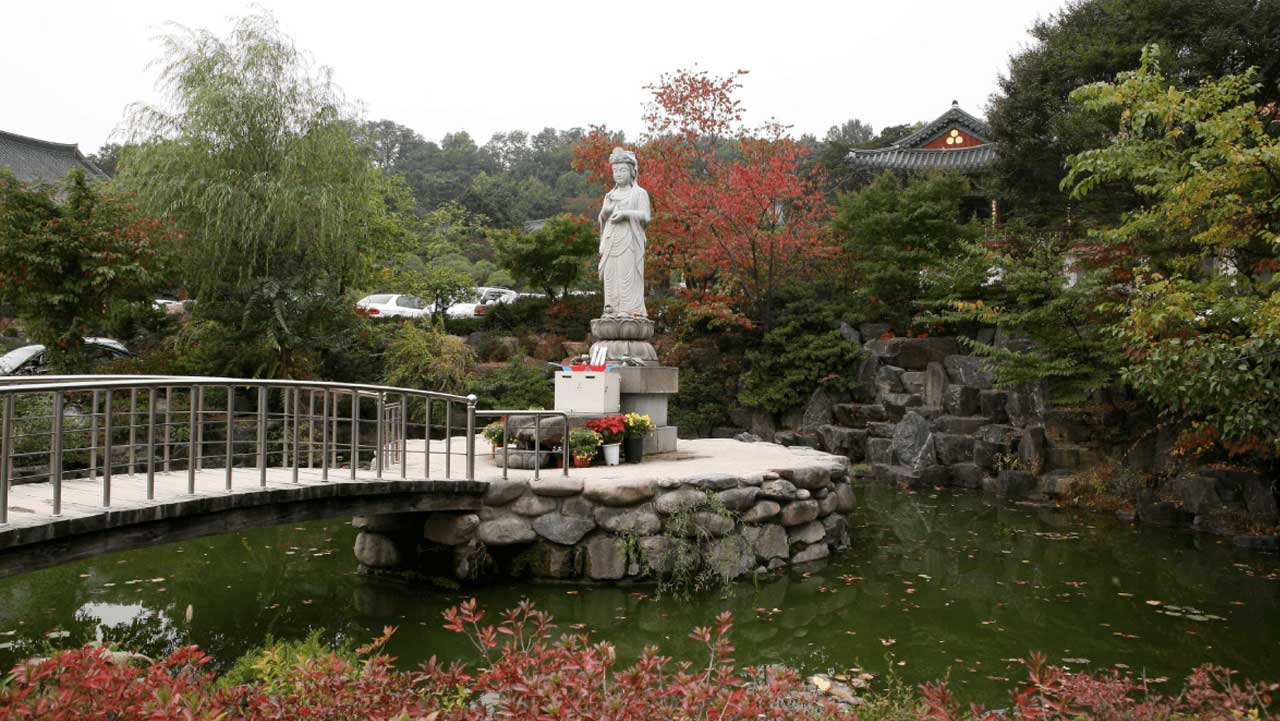 서울 봉은사 연못가의 불상과 단풍. 다리 너머로 전각 지붕이 보인다. / 한국관광공사 포토코리아-이범수