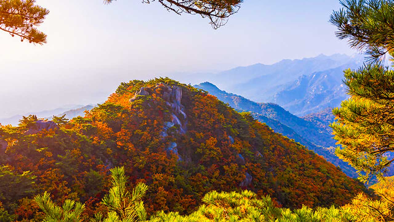 도봉산에서 바라본 주황빛 산비탈 너머로 북한산 쪽 산줄기가 겹겹이 이어진다. / 비짓서울